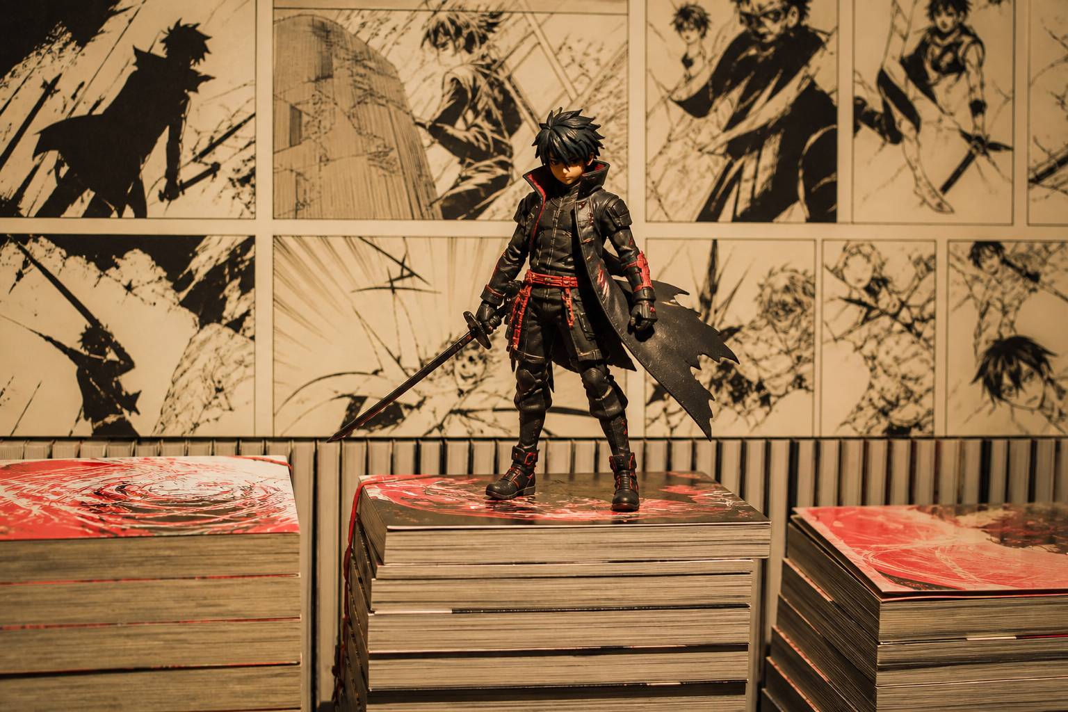Volumes de manga empilés avec figurine générique de jeune héros en tenue sombre